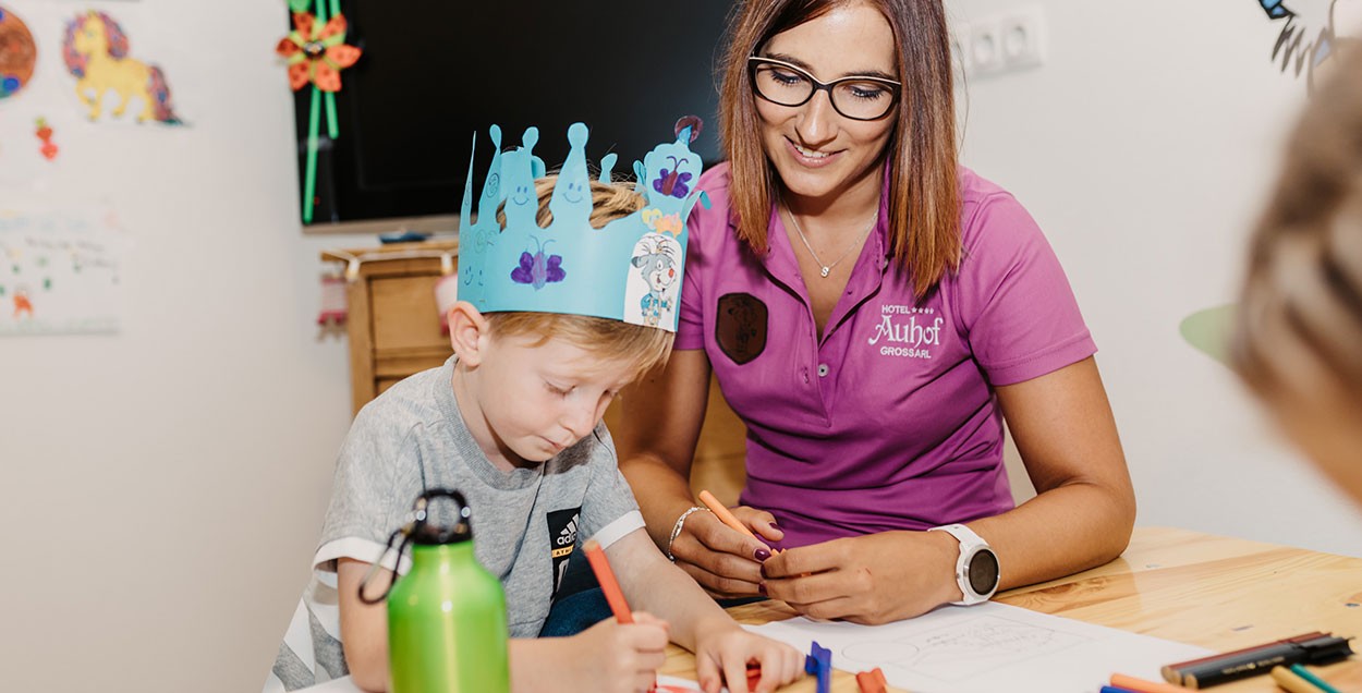 Kinderbetreuerin bastelt gemeinsam mit einem Gast Jungen 